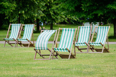 Six white and green striped outdoor garden chairs and green grass in a park in london, great britain