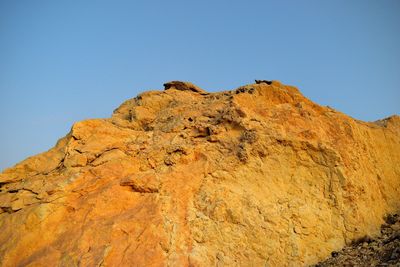 Low angle view of rock formations against clear blue sky