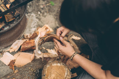 Woman removing bark of tree at camp