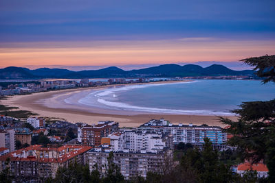 High angle view of sea and city against sky at sunset