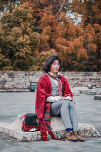 Portrait of young woman sitting in park during winter