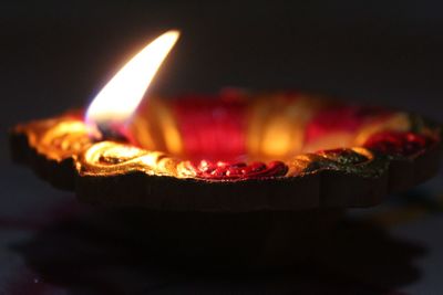 Close-up of burning diya in darkroom