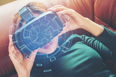 High angle view of woman enjoying virtual reality simulator on sofa