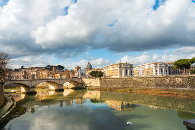 Arch bridge over river against buildings in city