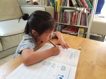 Rear view of girl sitting on table