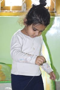 Close-up of cute girl standing against wall