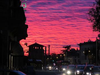 Cars on illuminated city against sky at sunset