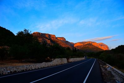 Road by mountains against blue sky