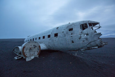 Abandoned airplane on land against sky