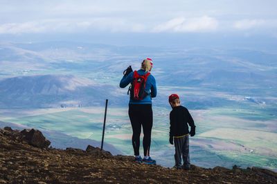 Rear view of men standing on mountain against sky