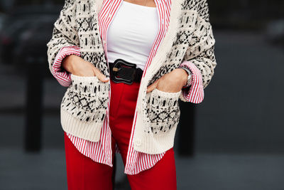 Close up hands in pockets of stylish woman. fashion blogger wearing sweater, shirt, belt and pants