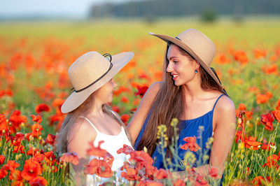 Side view of woman wearing hat standing by flowering plants