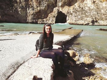 Portrait of smiling young woman sitting on rock