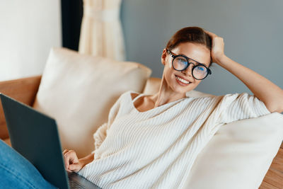 Young woman using mobile phone while sitting at home