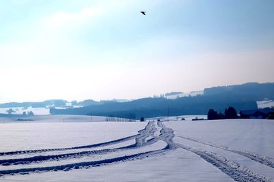 Tracks on snow covered field against sky