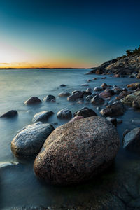 Rocks on beach against sky during sunset