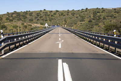 Road leading towards bridge against sky