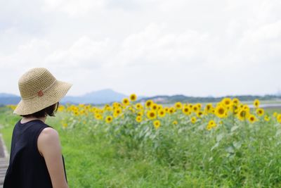 Rear view of woman wearing hat on field against sky