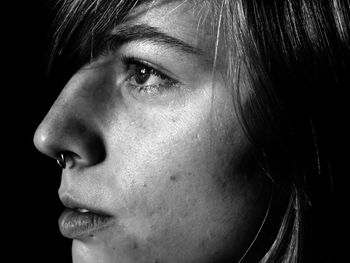 Close-up of thoughtful woman looking away against black background