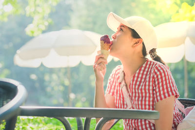 Woman eating ice cream while sitting at outdoors cafe