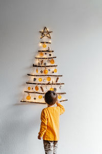 Rear view of boy standing against wall