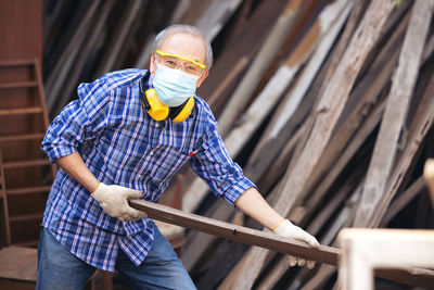 Carpenter, senior man sanding wooden fence in workplace using work tool