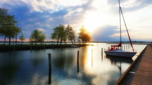 Boats moored at harbor against sky during sunset