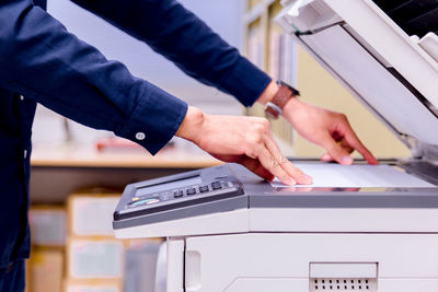 Midsection of businessman using photocopier in office