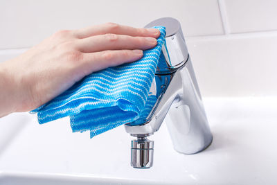 Close-up of person cleaning sink in bathroom