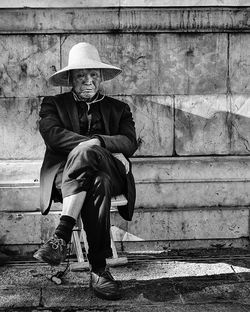 Portrait of man sitting on staircase against wall