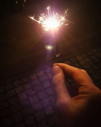 Close-up of hand holding sparkler at night