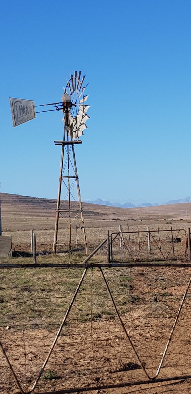 WINDMILL ON FIELD AGAINST CLEAR SKY