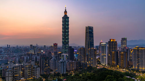 Skyscrapers in city against sky during sunset