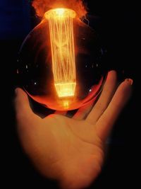 Close-up of hand holding illuminated light bulb