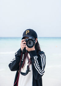 Portrait of man photographing against sky