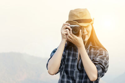 Woman photographing against sky