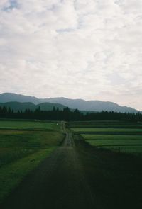 Scenic view of grassy field against cloudy sky