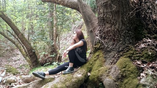 Man standing on tree trunk in forest