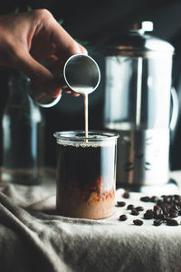 Close-up of hand pouring coffee in cup