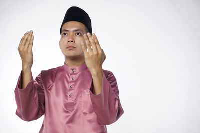 Portrait of young man looking away against white background