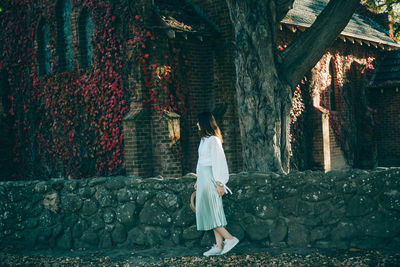 Side view of woman standing against house