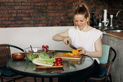 Young woman preparing vegetarian greens salad at home