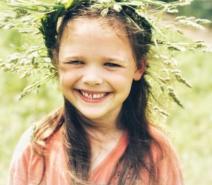 Portrait of smiling girl wearing plant stems