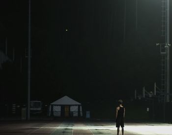 Woman walking on illuminated road at night