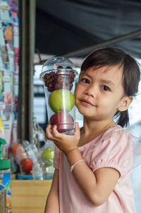 Portrait of smiling girl holding fruits in container