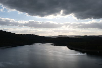 Scenic view of lake by silhouette mountain against sky