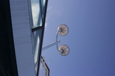 Low angle view of electric lamp against blue sky