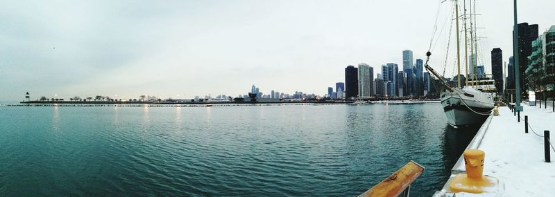 View of city at waterfront against cloudy sky