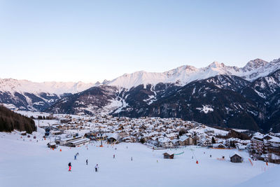 People skiing on snow covered field against sky