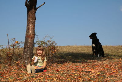 Girl with drink and dog on field during autumn